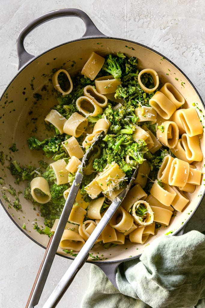 big pot of pasta with broccoli and tongs