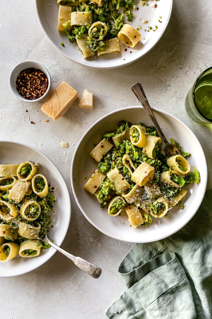 broccoli pasta in two bowls with a fork and chili flakes on the side