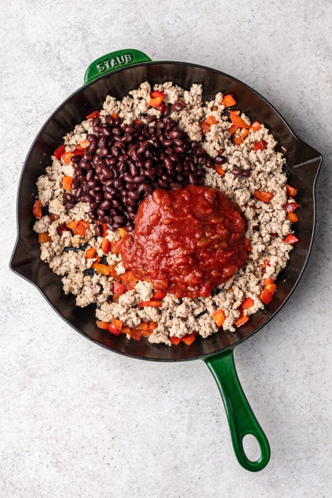 cast iron skillet with chopped bell peppers, ground turkey, salsa and black beans