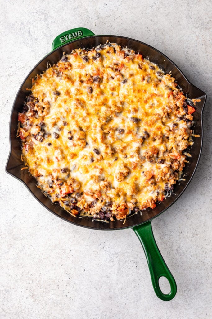 turkey taco skillet with chopped veggies topped with melted cheese