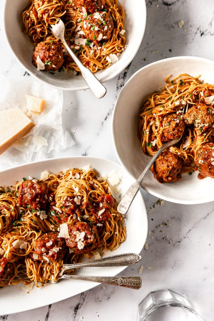 overhead shot of meatballs in two bowls and a serving platter with spaghetti