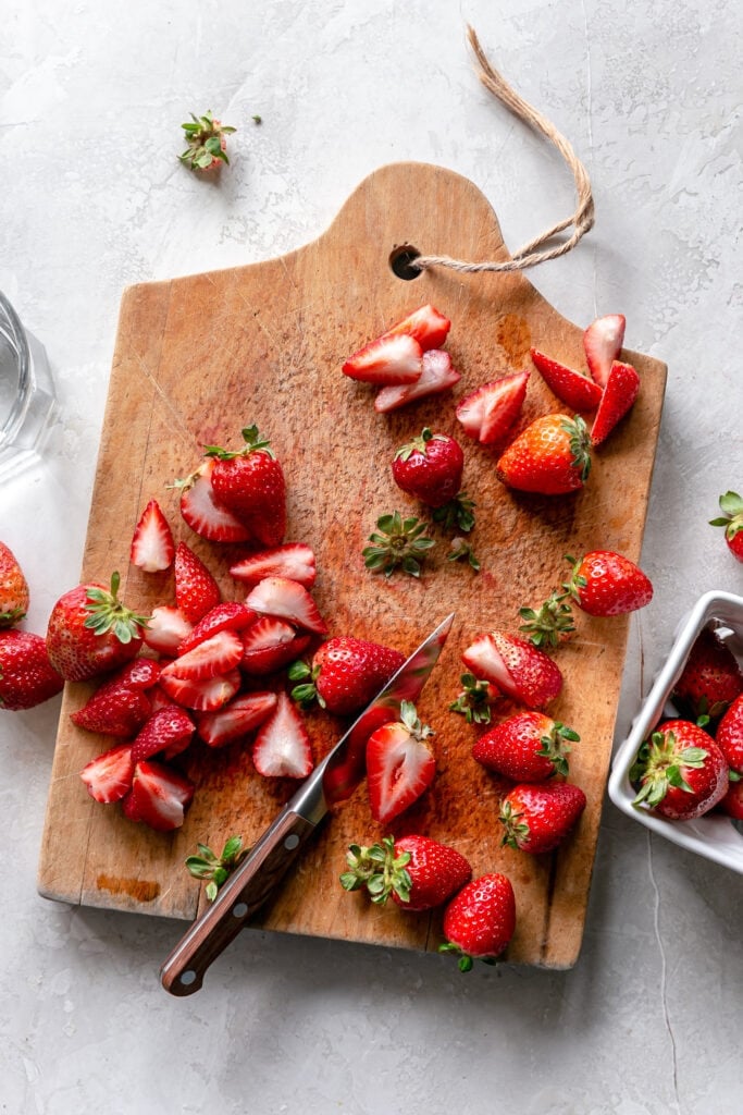 overhead shot of sliced strawberries on a wood cutting board