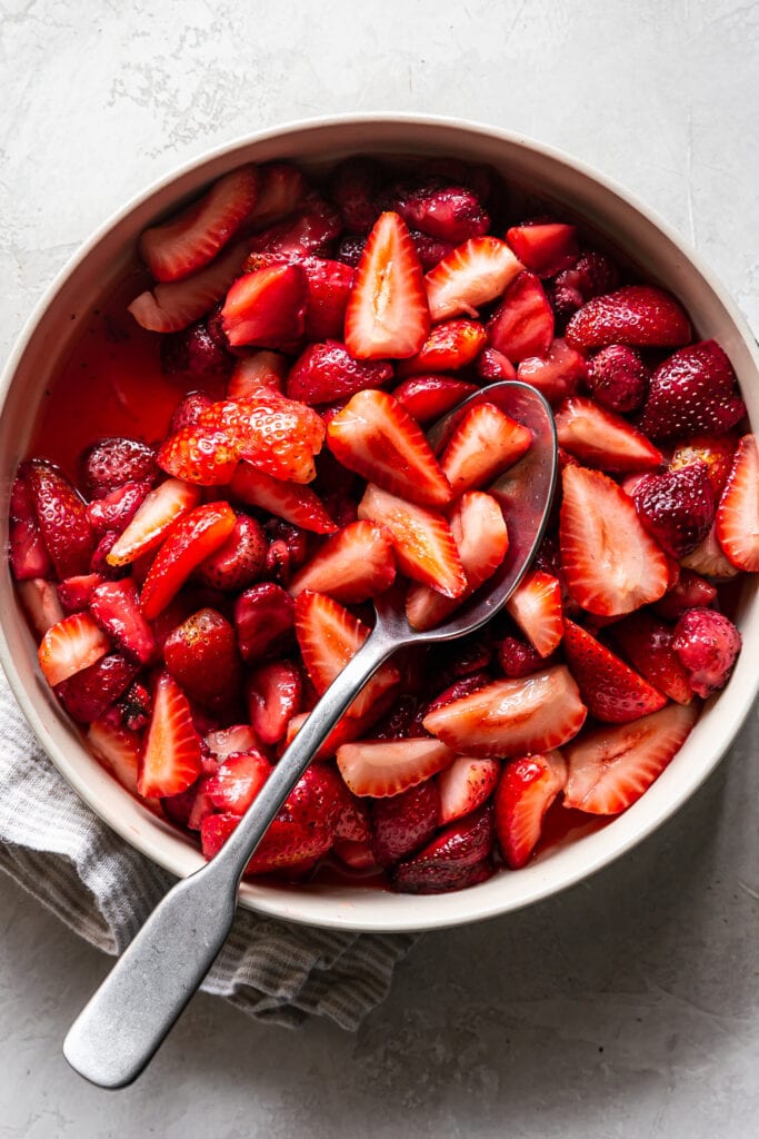bowl of marinated sliced strawberries with a spoon