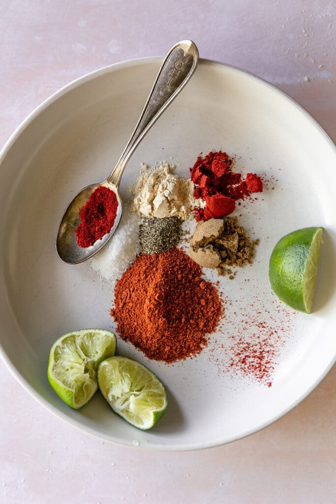 overhead photo pf spices in a bowl with lime and spoon