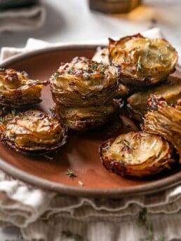 Crispy baked and stacked garlic butter potatoes on a brown plate