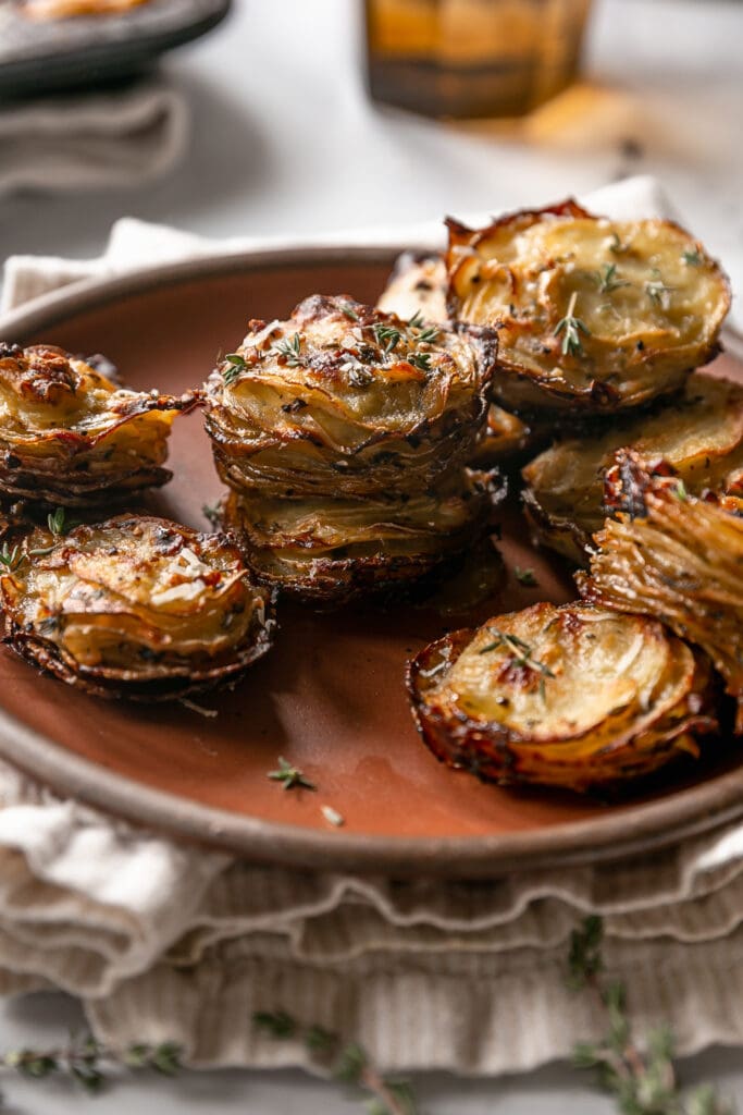 Crispy baked and stacked garlic butter potatoes on a brown plate