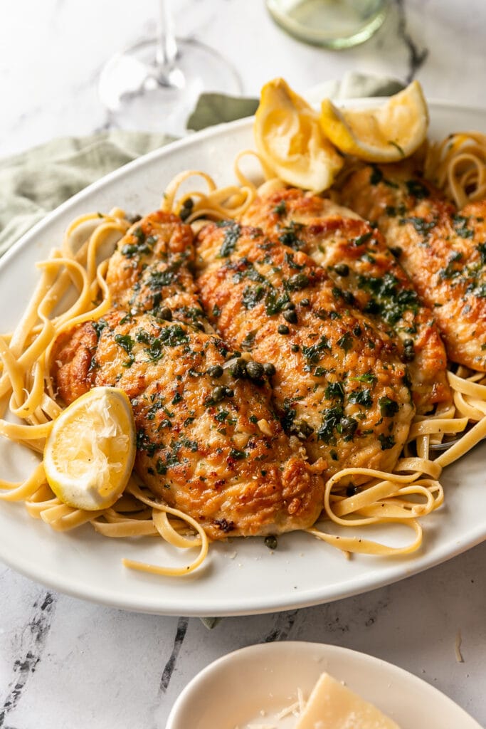 Chicken Piccata on a plate of pasta with a lemon slice