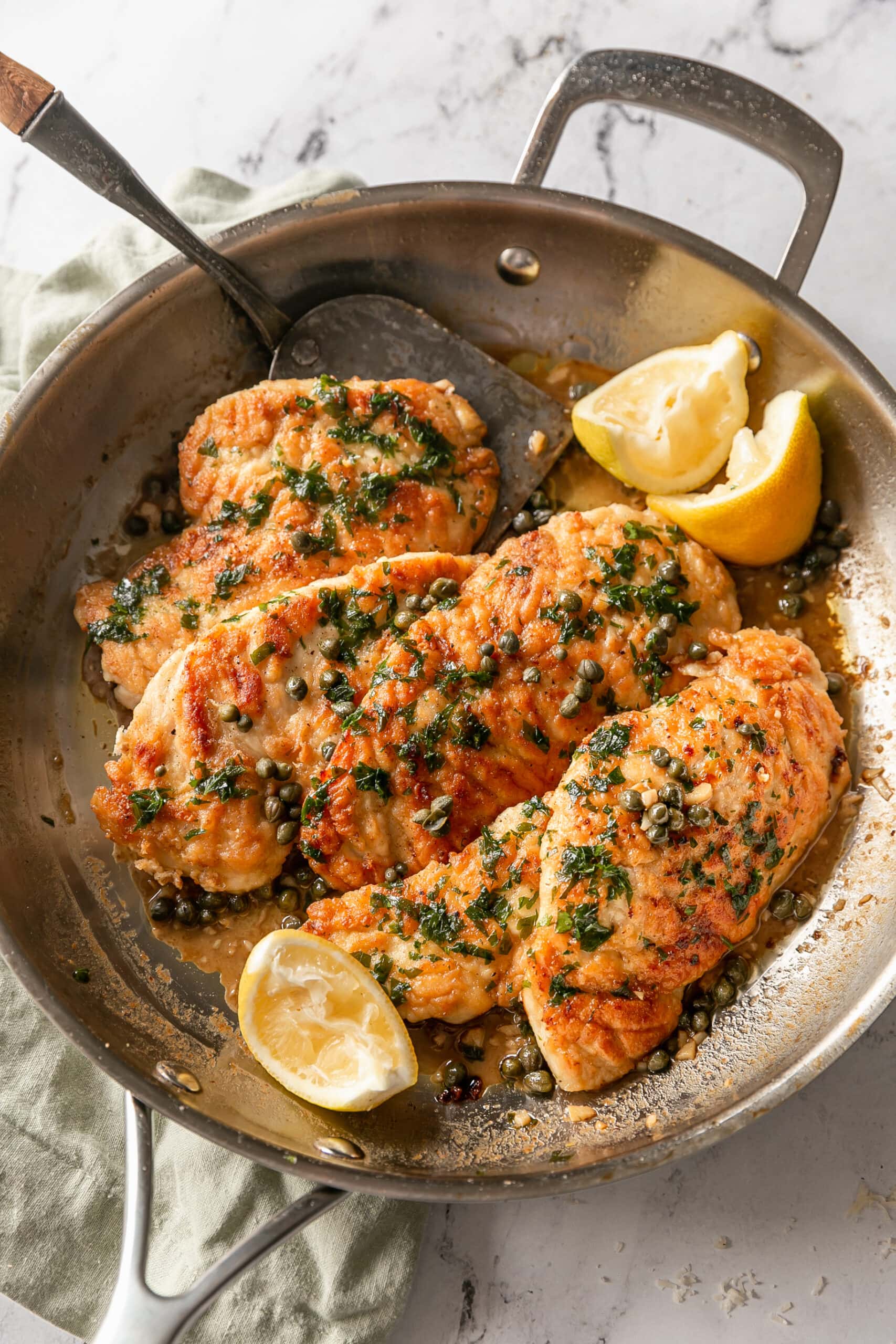 Finished Chicken Piccata in pan with lemon wedges