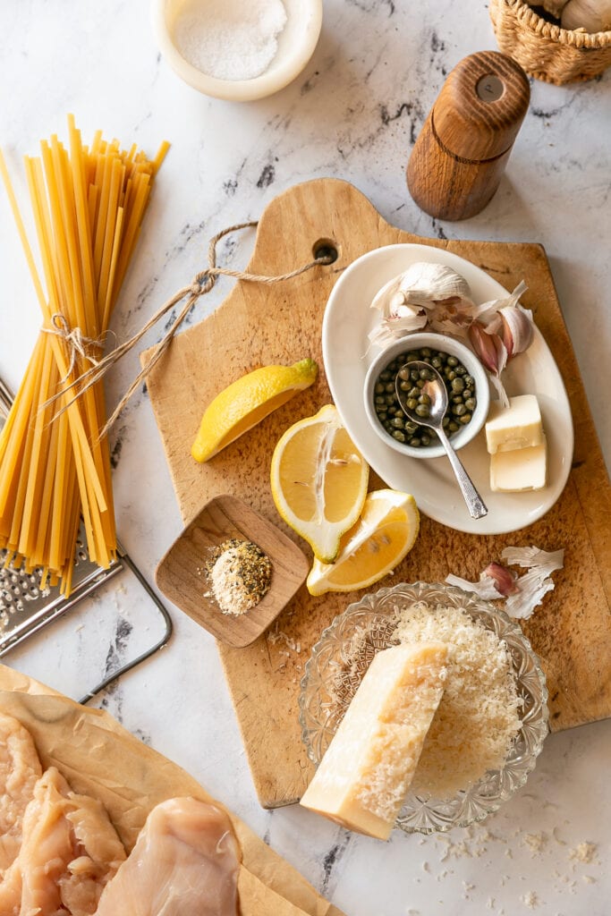 Chicken Piccata ingredients on a wooden cutting board