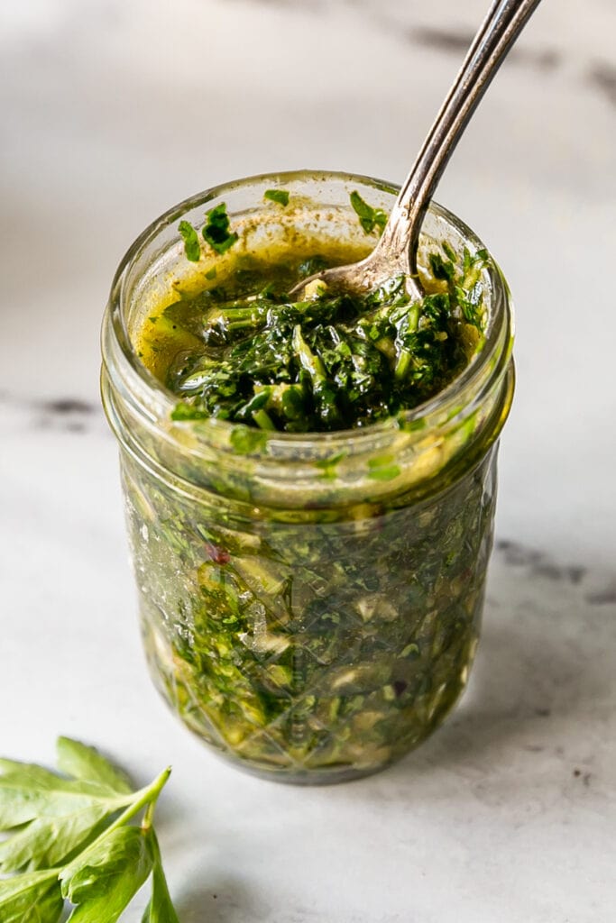 Close up of Chimichurri in glass jar with a spoon