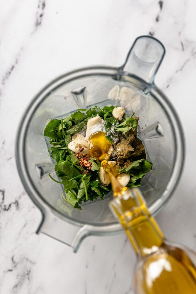 7-Ingredient Chimichurri - parsley, spices, garlic in blender pouring in olive oil