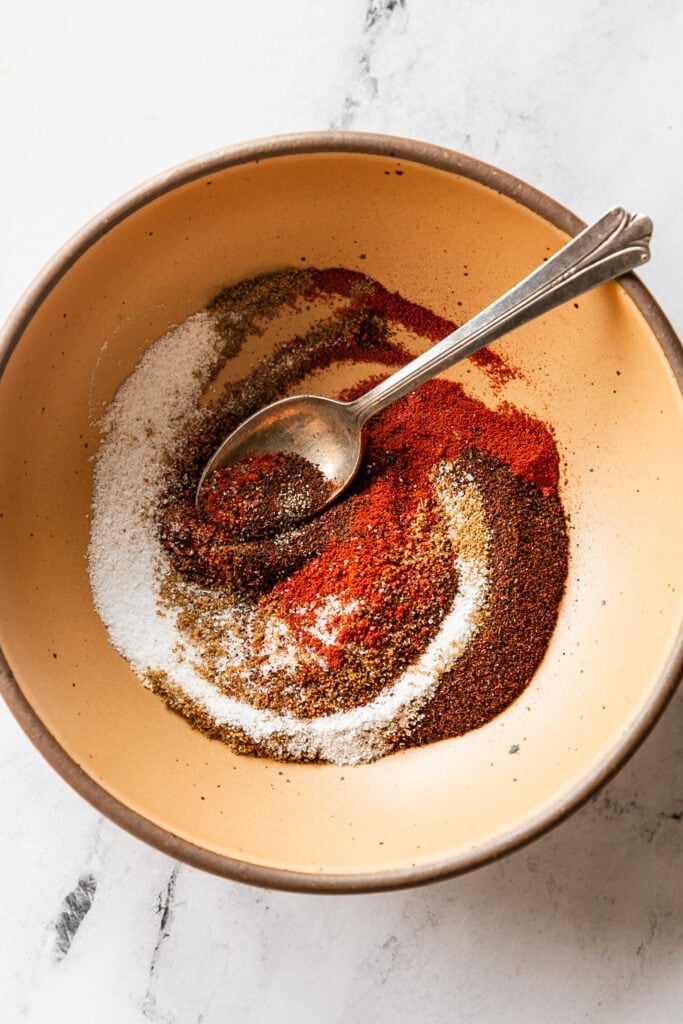 Mild spices being mixed with spoon in orange bowl