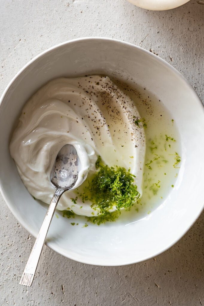 Easy 4-Ingredient Lime Crema - whisking yogurt, lime juice and lime zest in a bowl
