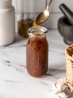 Easy Homemade Teriyaki Sauce - teriyaki sauce on spoon in a glass jar on marble countertop