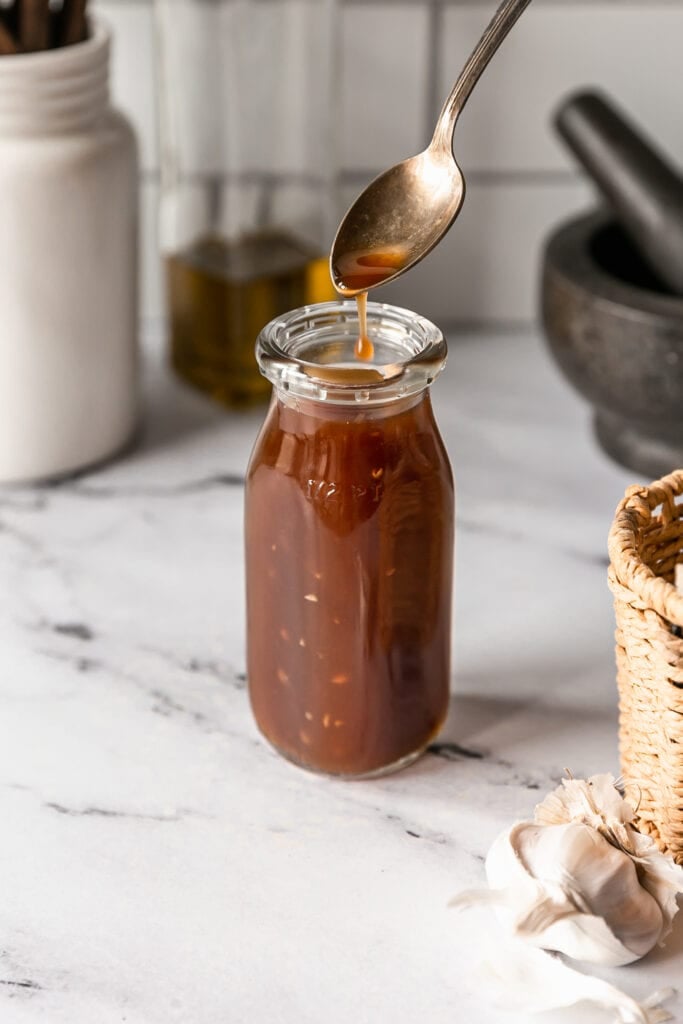 Easy Homemade Teriyaki Sauce - teriyaki sauce on spoon in a glass jar on marble countertop