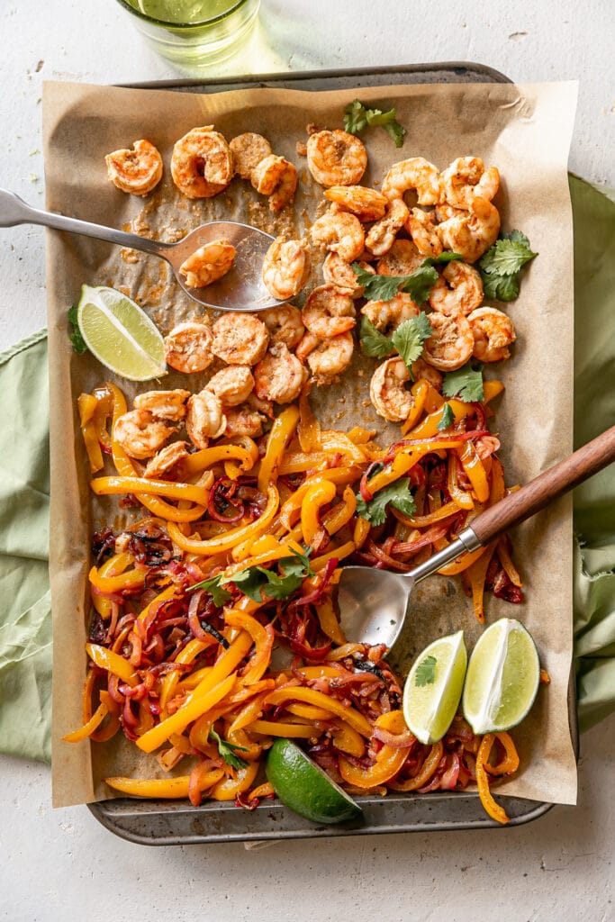 LIBAD Sheet Pan Shrimp Fajitas with Lime Crema - cooked shrimp, pepper and onion on sheet pan with cilantro and limes