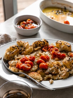 Cauliflower Steaks with Tomato Garlic Confit - roasted cauliflower steaks on white platter with tomato confit