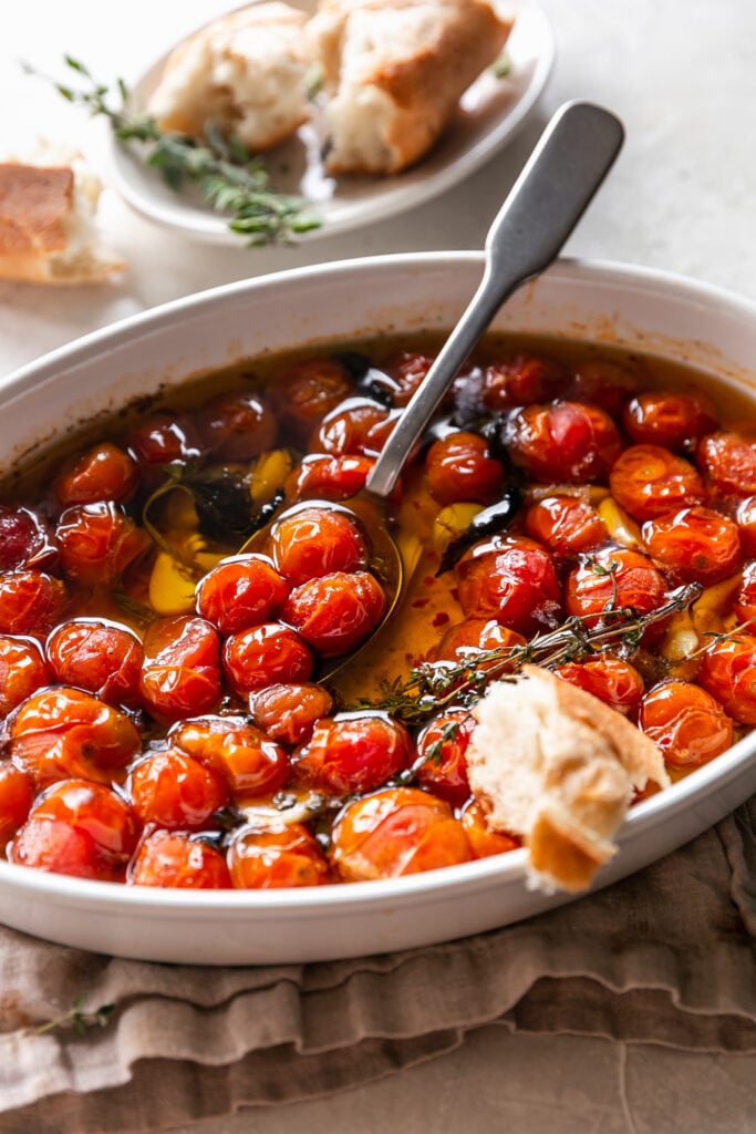 Quick Tomato Garlic Confit - roasted cherry tomatoes, herbs and garlic with spoon and bread