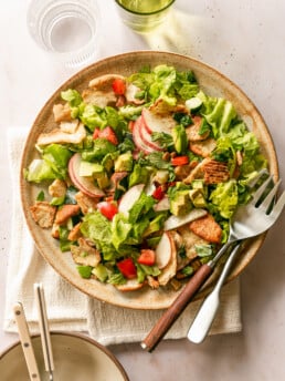 Summer Fattoush Salad tossed on platter with serving utensils, glasses and bowls