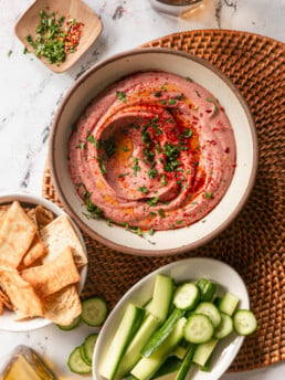 5-Minute Blender Beet Hummus - beet hummus swirled in bowl with cucumber and pita chips