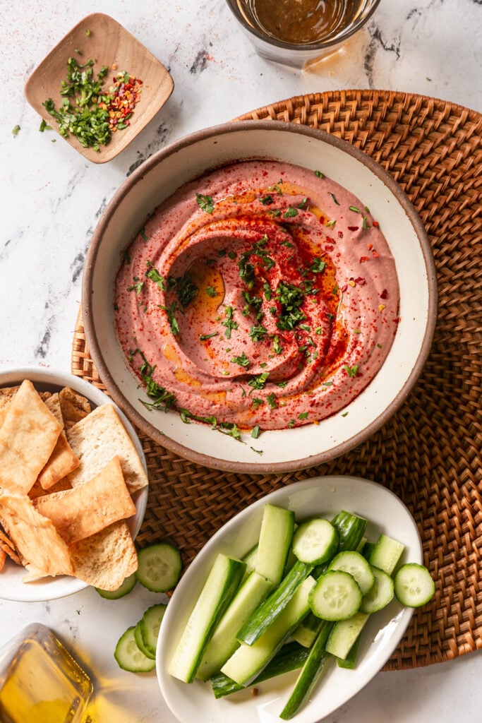 5-Minute Blender Beet Hummus - beet hummus swirled in bowl with cucumber and pita chips