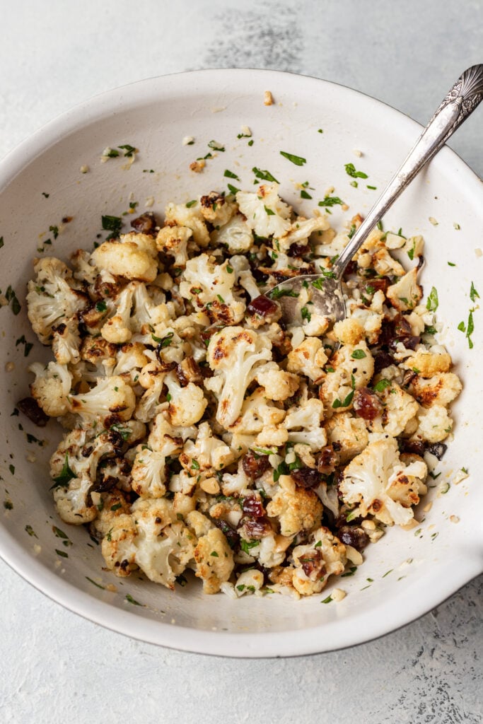 cauliflower tossed with chopped dates, nuts and parsley in a bowl