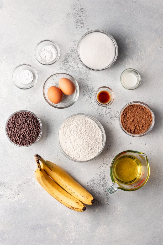 ingredient shot of bananas, sugar, flour, eggs, chocolate chips in bowls