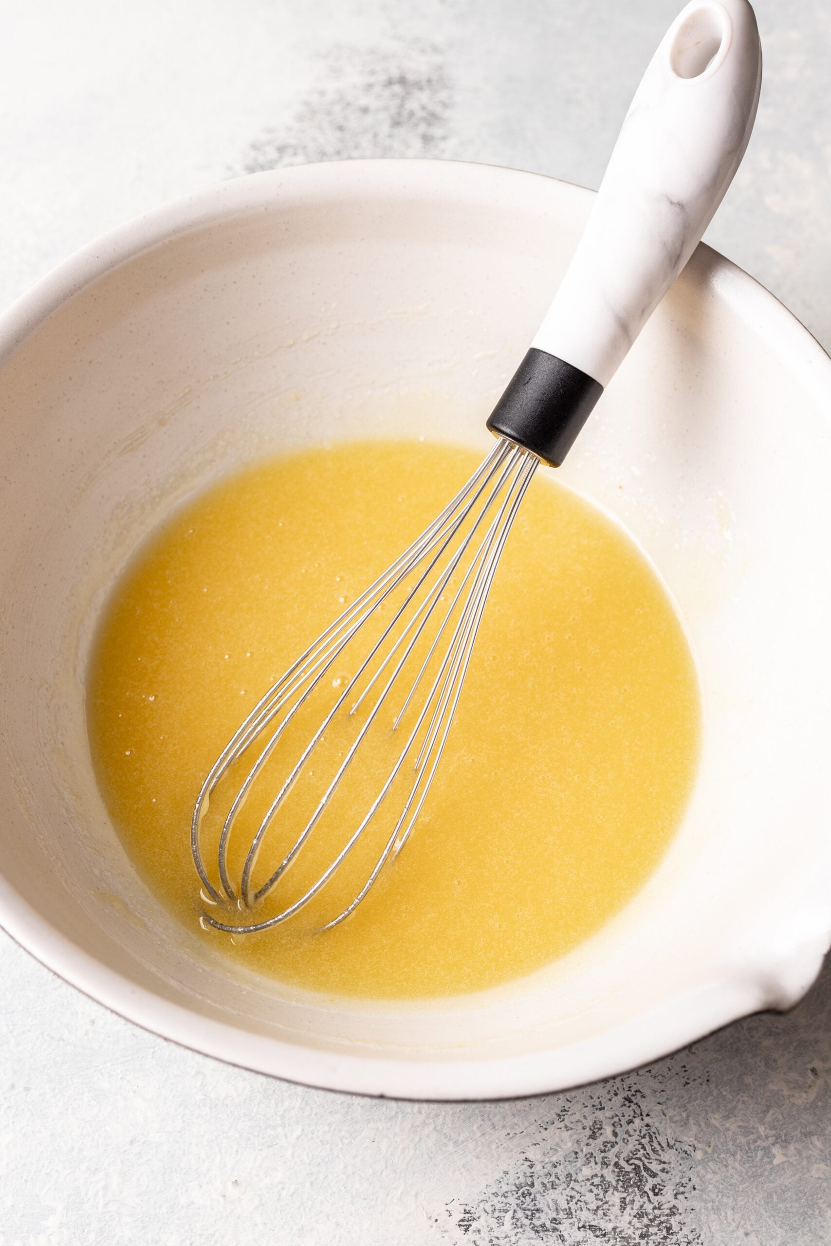 eggs and sugar mixed in a bowl with a whisk