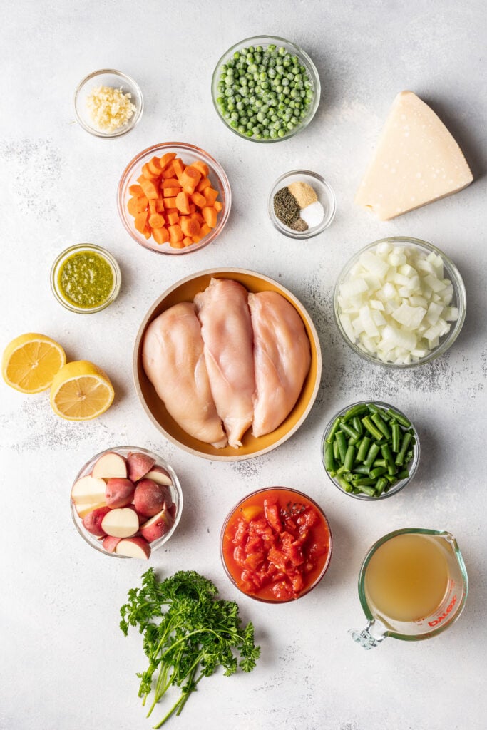 shot of ingredients. raw chicken, carrots, peas, lemon, potatoes