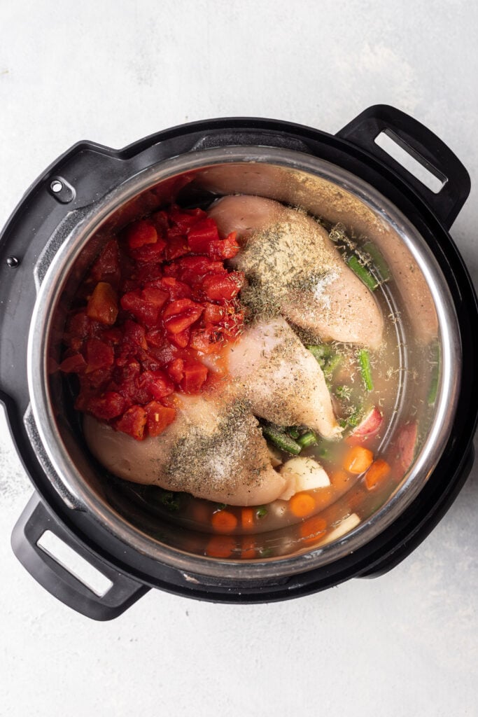 overhead shot of instant pot with chicken, diced tomatoes and veggies