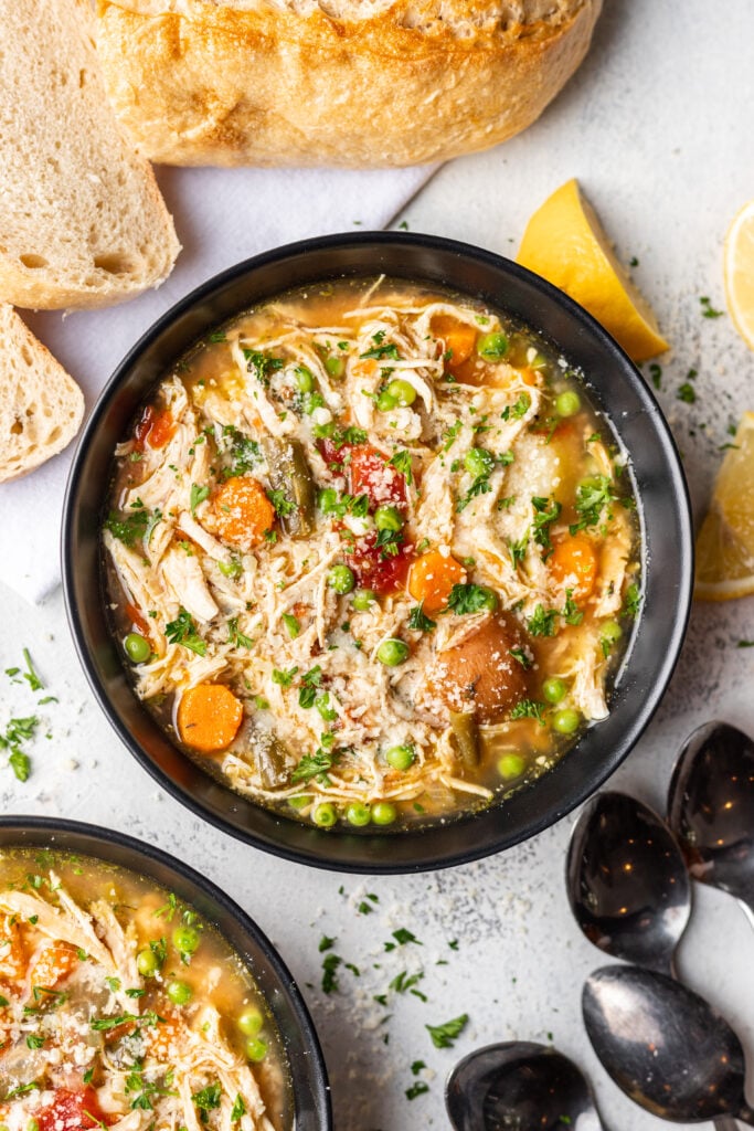 black bowl full of chicken vegetable soup with a spoon in it