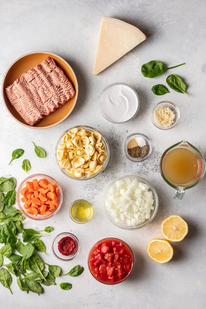 ingredients in bowls on a board like ground turkey, chopped carrots, tortellini, onions