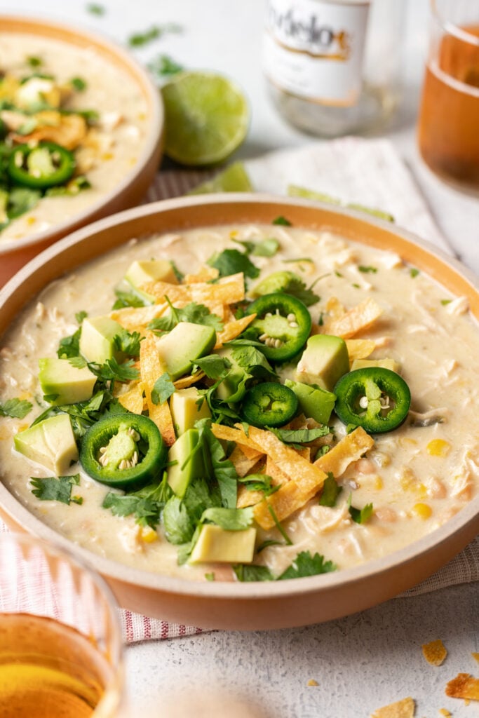 white chicken chili in a bowl with jalepenos, cheese and avocado on top