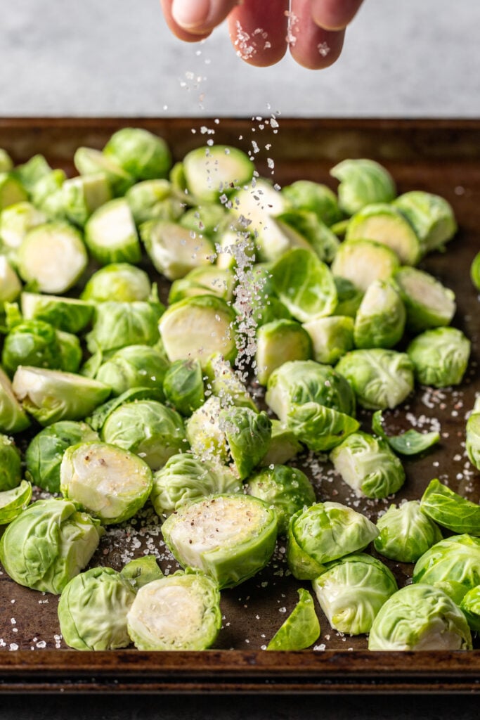 raw brussles sprouts on a sheet pan sprinkled with salt