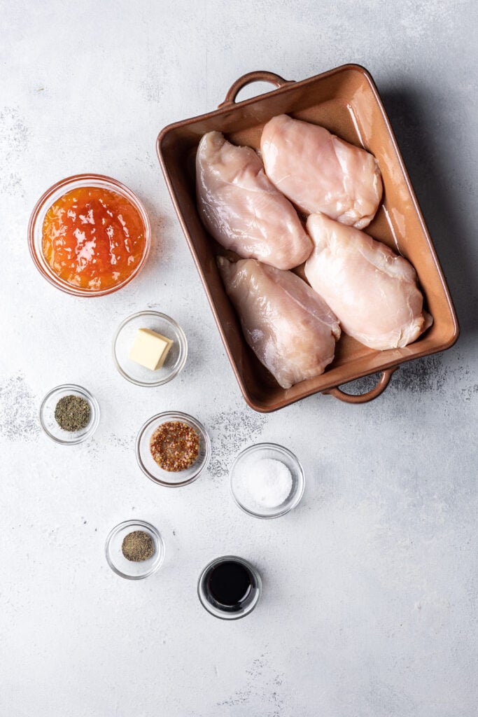 ingredients on a board such as raw chicken, spices and apricot jam
