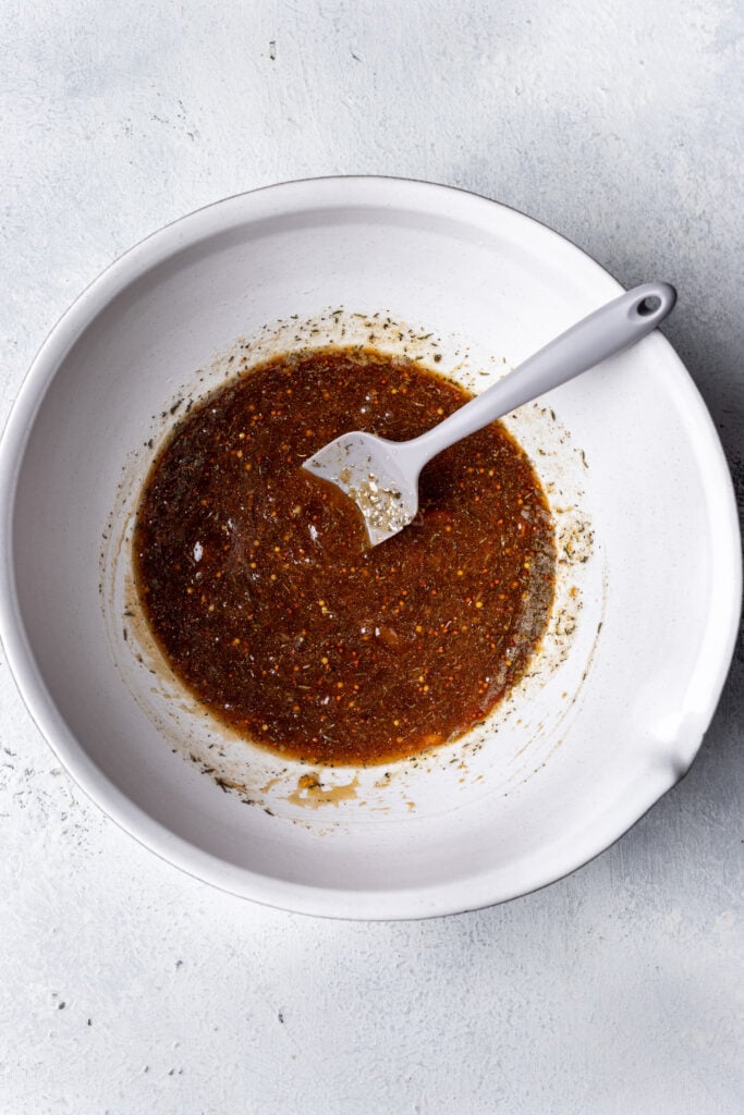 a white bowl with apricot marinade and a spoon