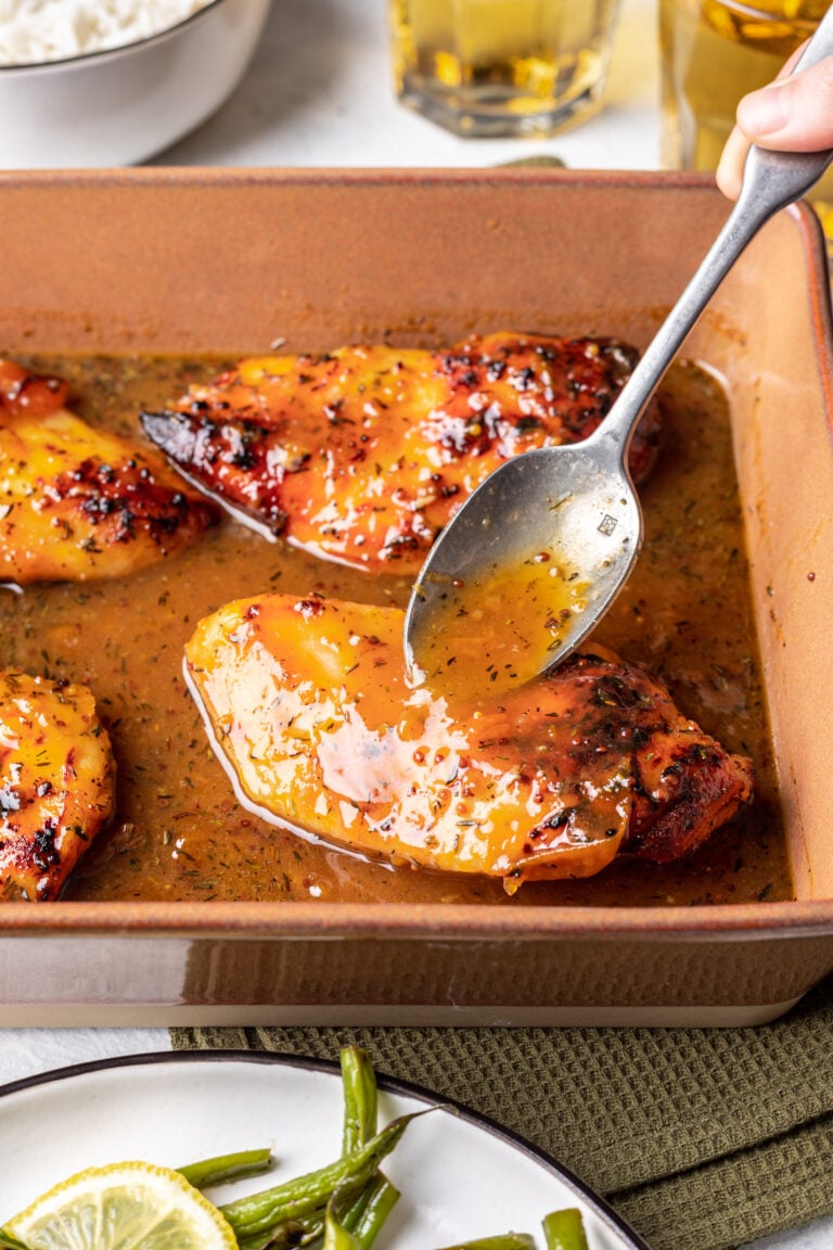 apricot sauce being spooned over baked chicken
