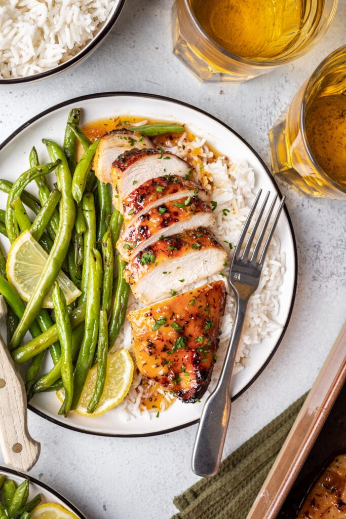 sliced chicken on a plate with rice and green beans