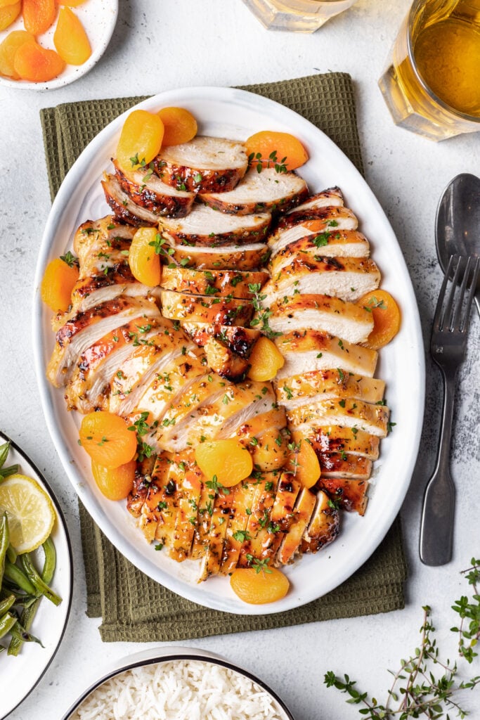 sliced chicken with apricots on a white platter
