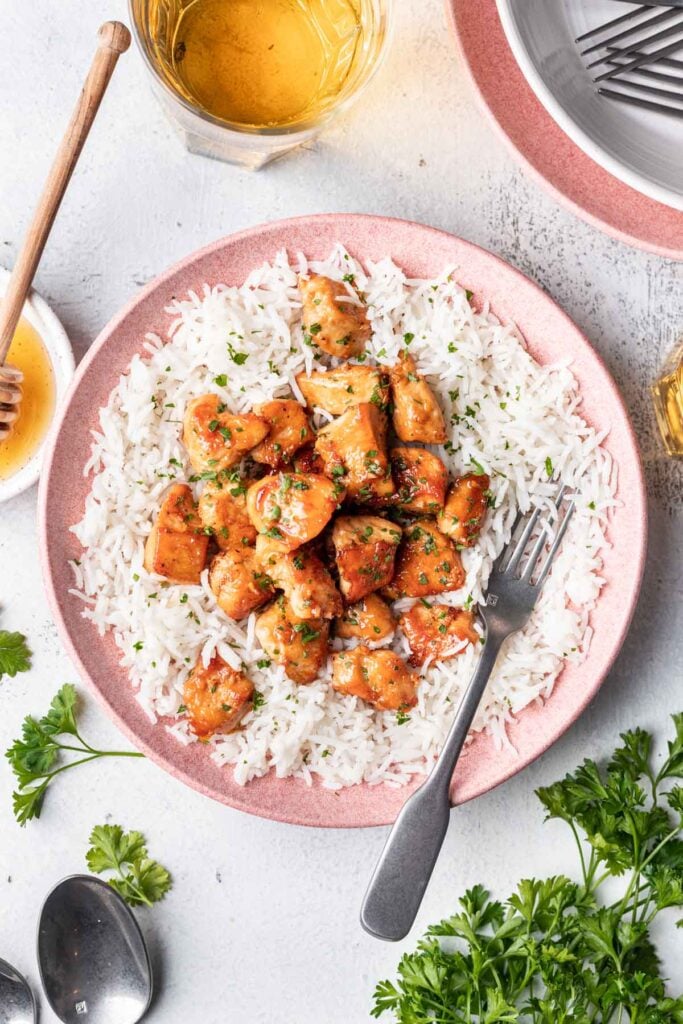 chicken on a bed of rice served on a pink plate