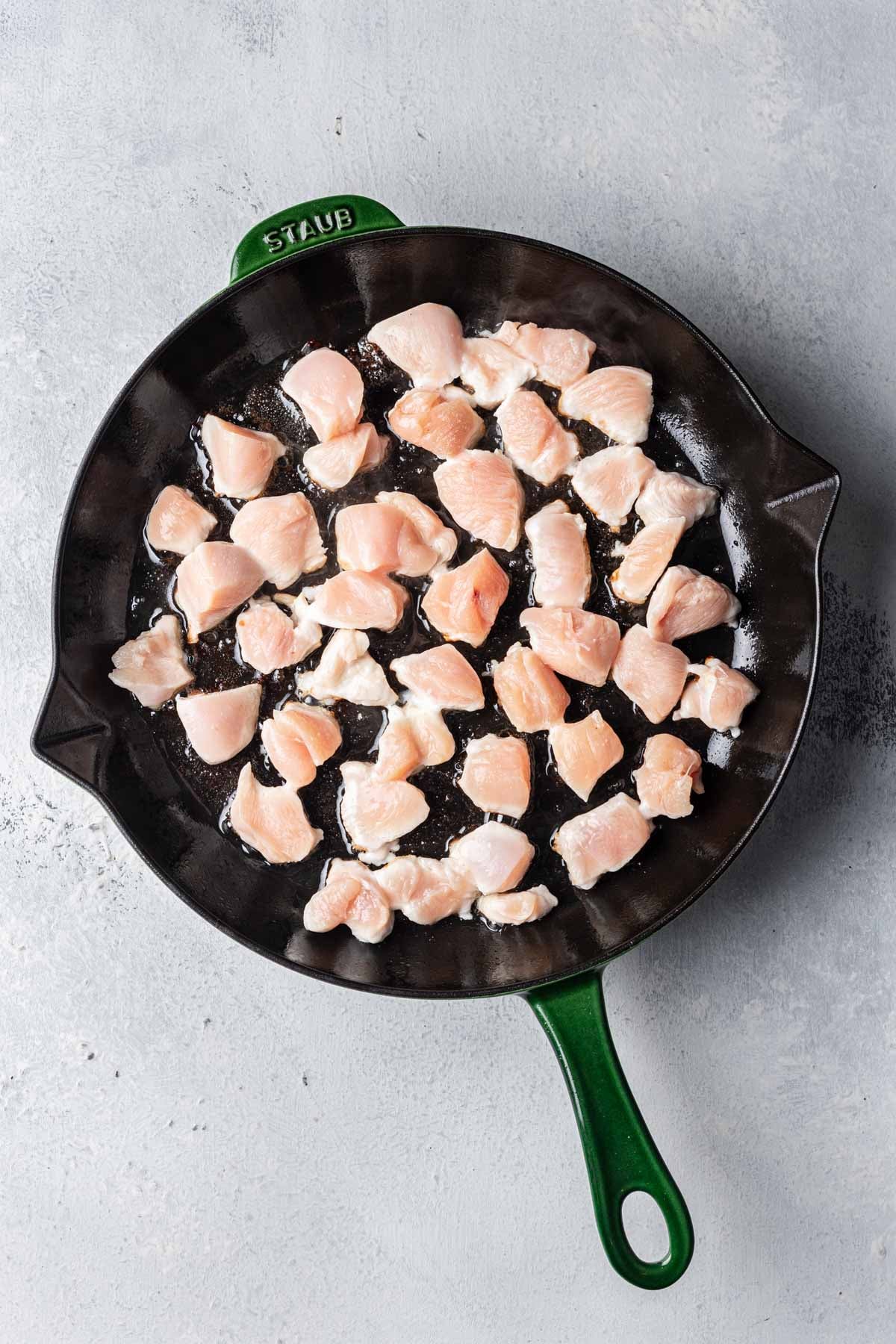 chicken pieces cooking in a pan