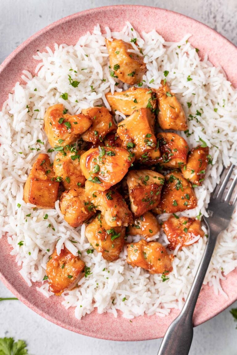 chicken on a bed of rice served on a pink plate