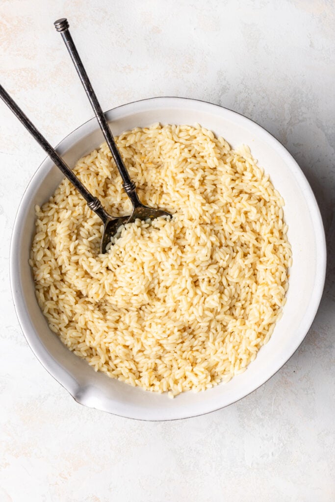 cooked orzo in a bowl with serving spoons