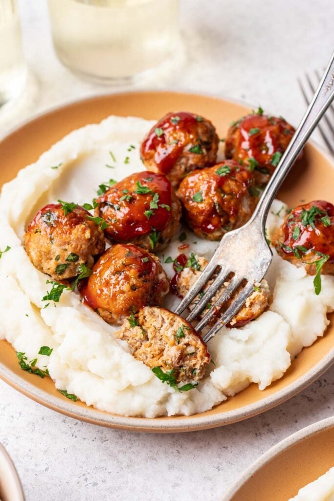meatballs on a plate with mashed potatoes and a fork