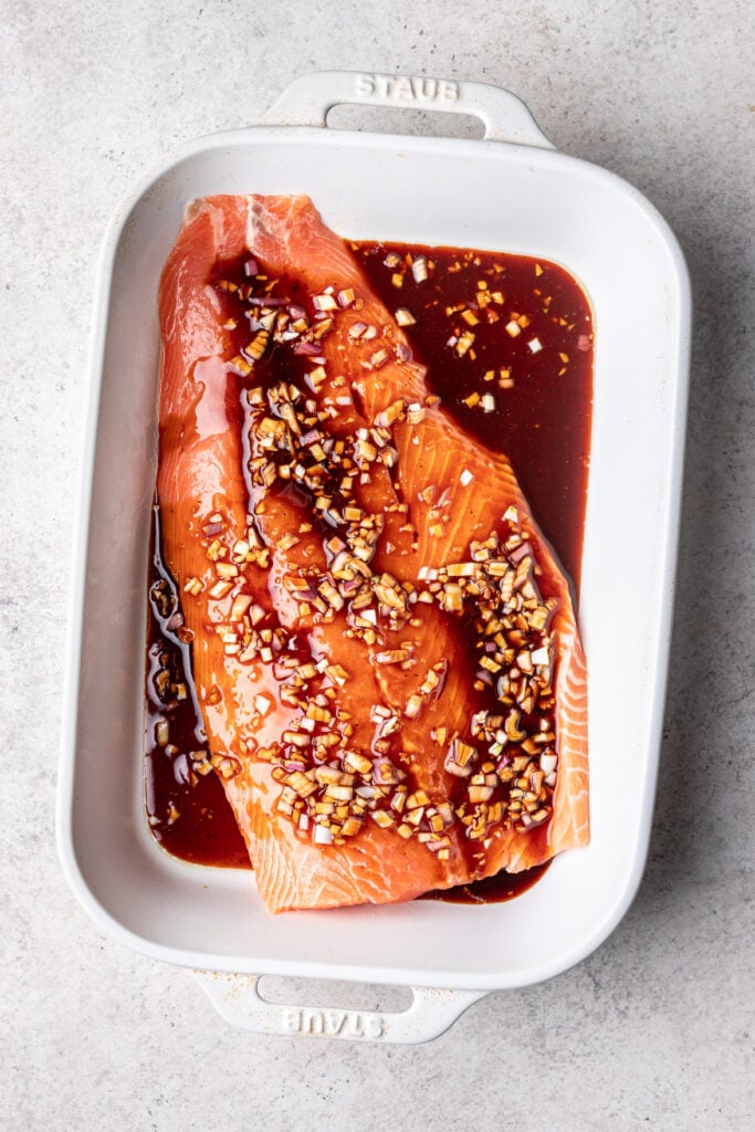 salmon in a white baking dish with marinade