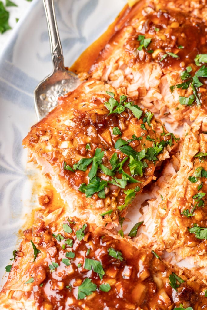 cooked salmon on a white platter being scooped with spatula