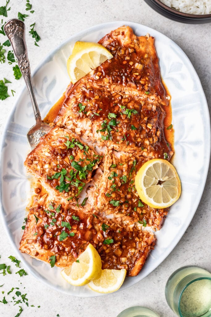 cooked salmon on a white platter being scooped with spatula