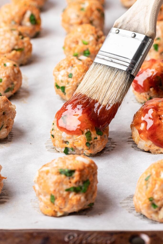 brushing sauce on a meatball