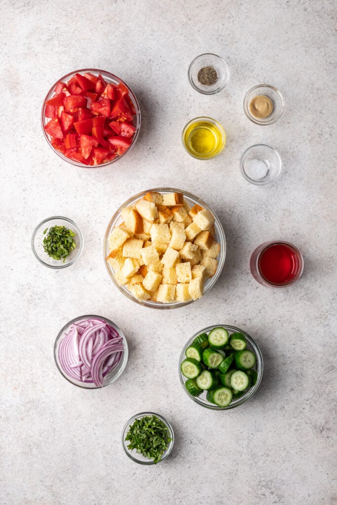 ingredients in separate bowls like tomatoes, cubed bread, cucumber and red onion