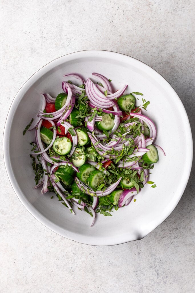 cucumber and red onion in a white bowl